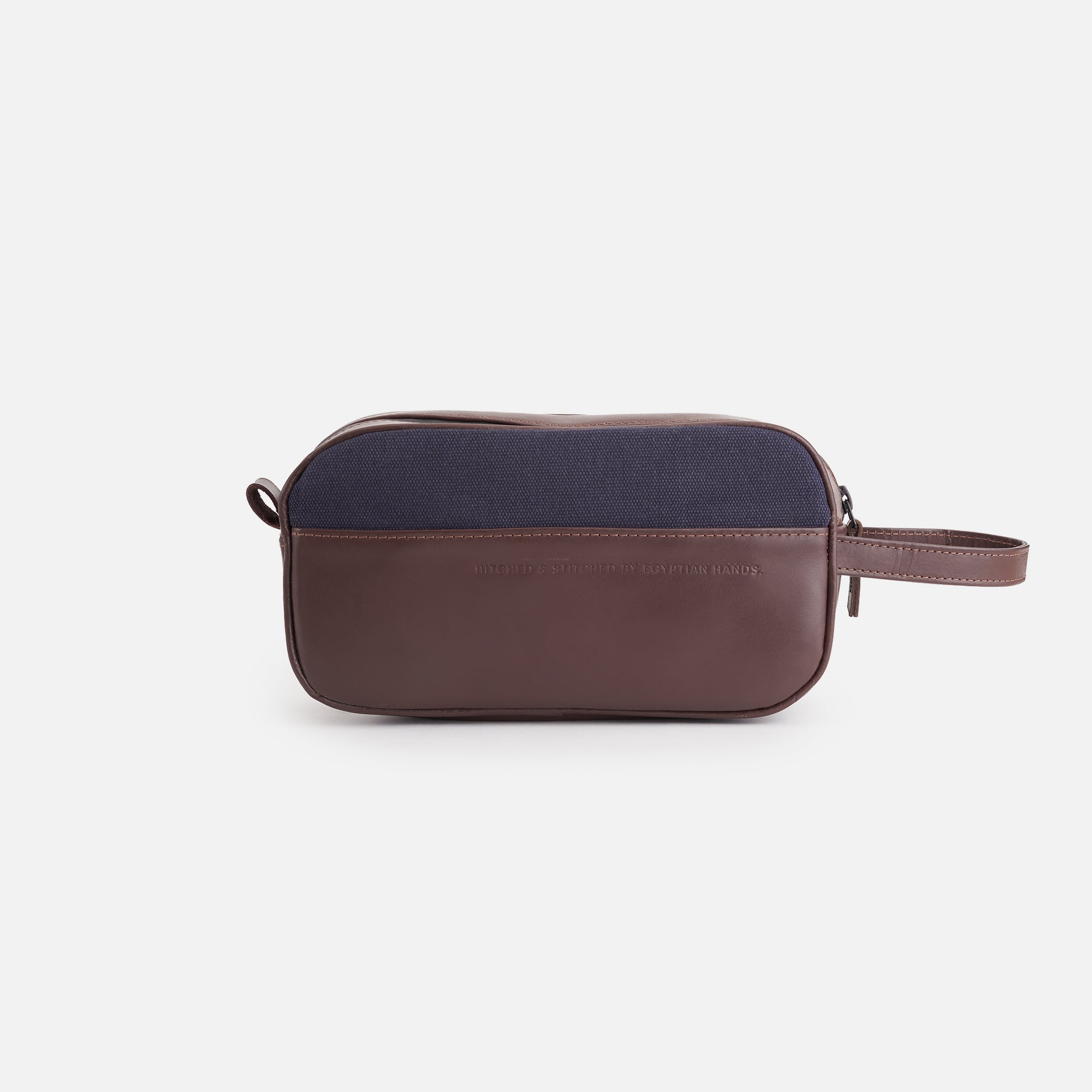 Navy and brown leather toiletry bag with wrist strap on white background.