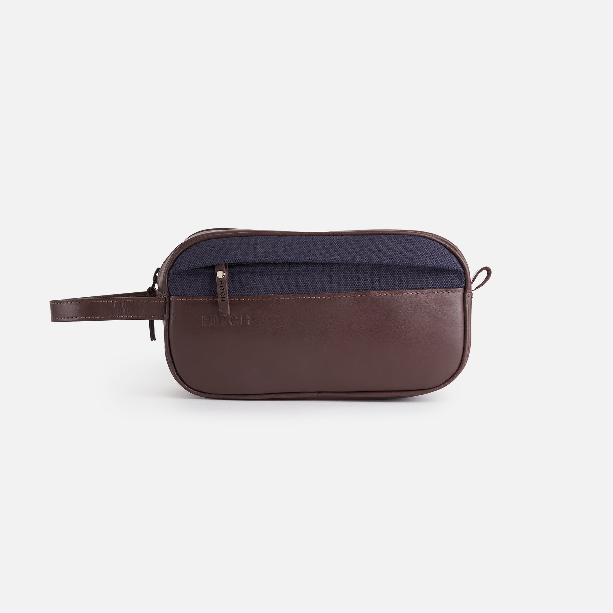 Designer brown leather Dopp kit with navy fabric detail, embossed HITCH, on white background.