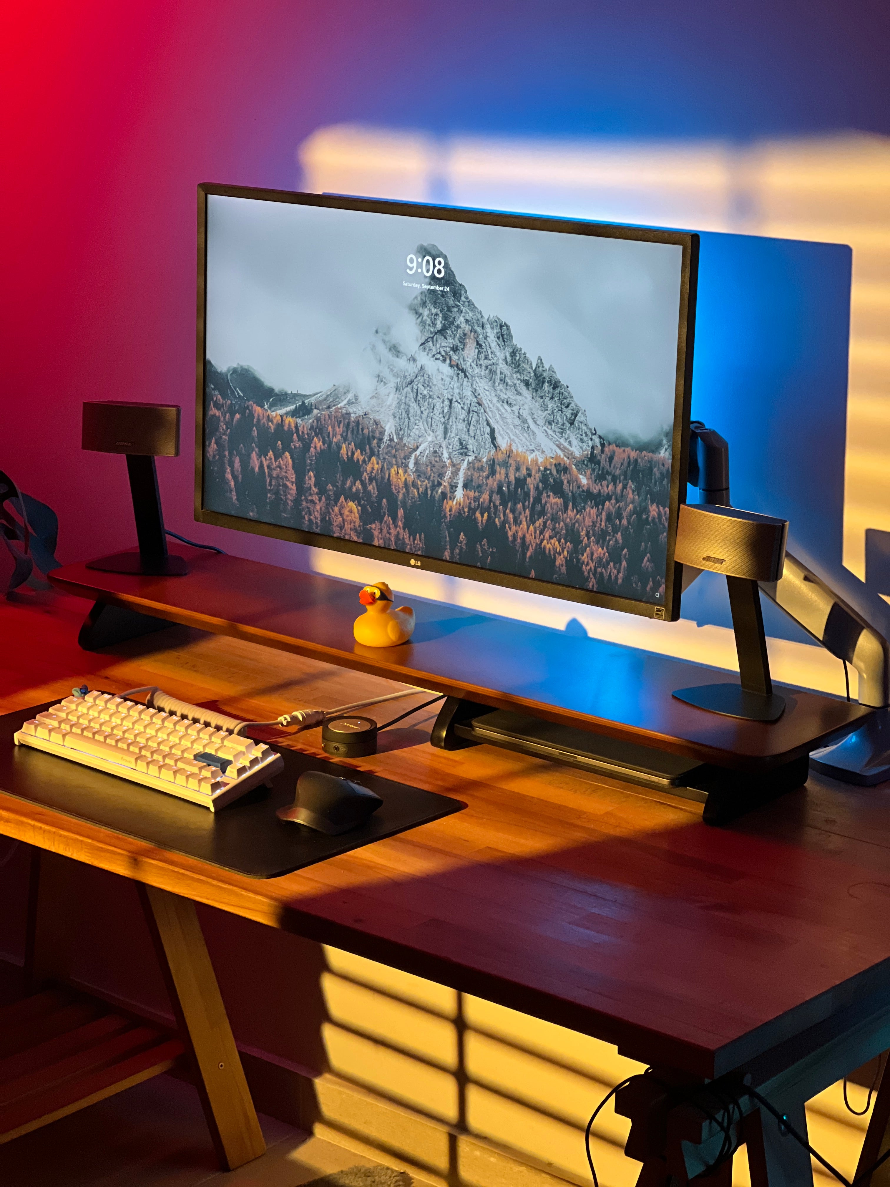 Modern computer setup with LED backlighting on woodsy wooden desk shelf.